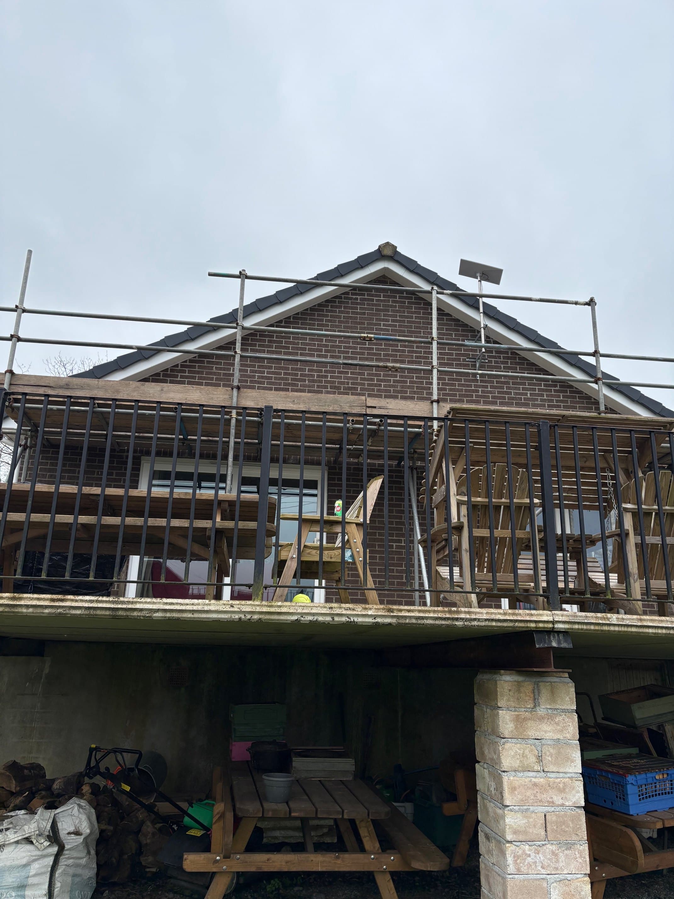 Full house elevation mid-job — scaffolded, fascia stripped exposing rafters before new UPVC install.